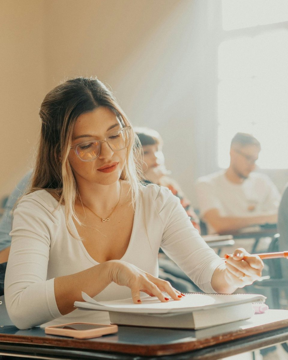 Estudante universitária escrevendo o próprio trabalho em sala de aula
